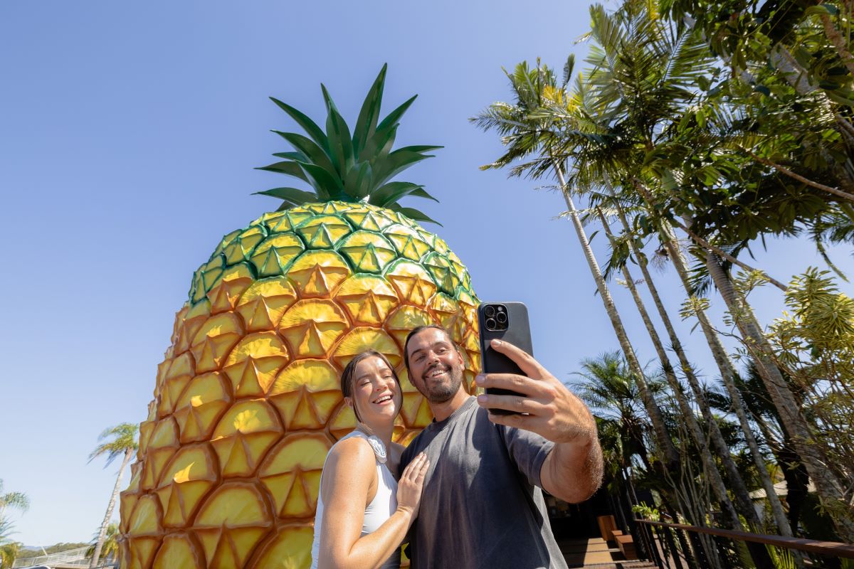 A young couple taking a selfie in front of the Big Pineapple