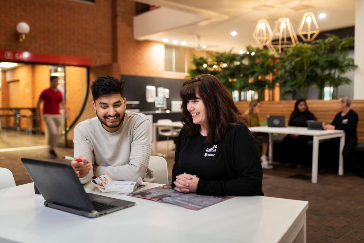 A student and teacher at TAFE SA at a desk with a laptop