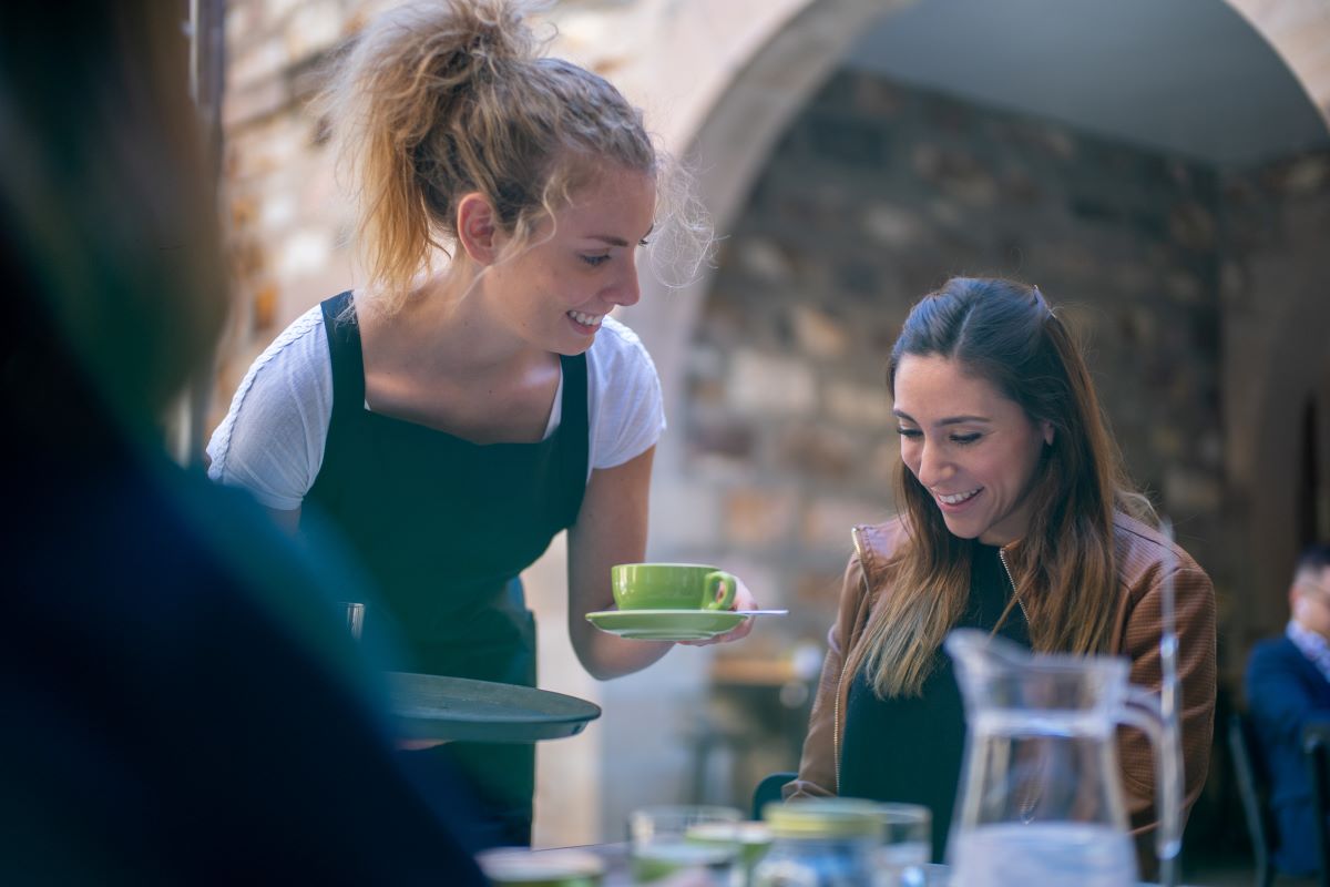 A waitress serving a cup of coffee with a smile