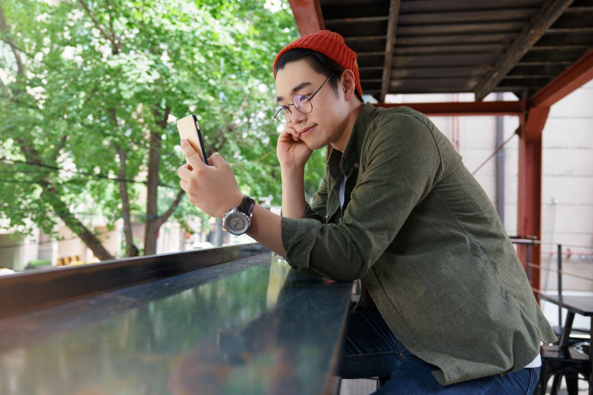 A male international student is on a balcony looking at his phone