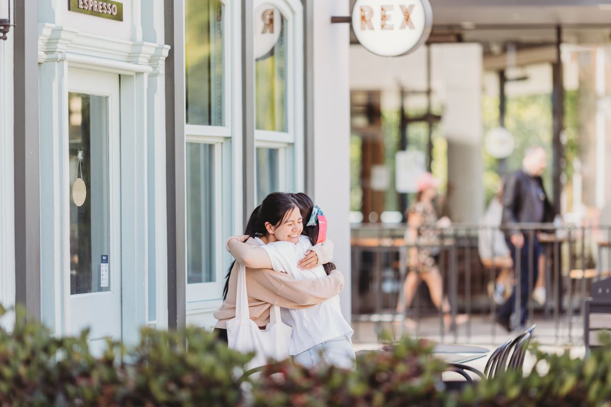 Two friends hugging outside a cafe