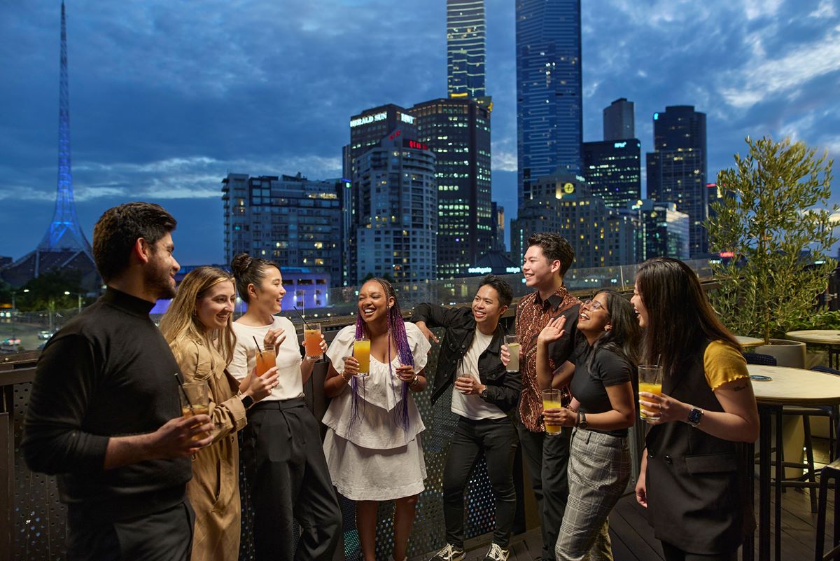 A group of friends standing with drinks at a rooftop bar in Melbourne