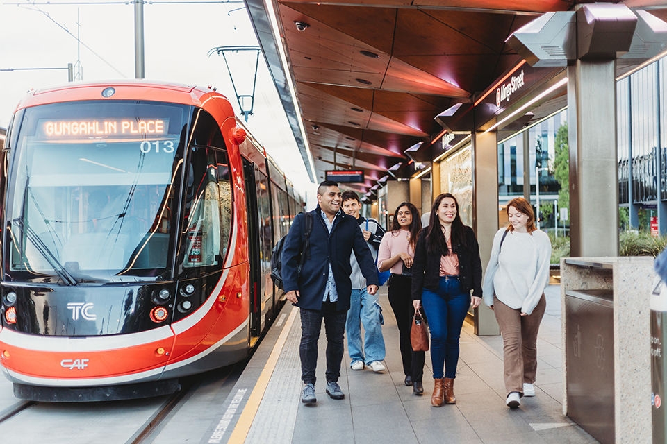 A group of students hop off the light rail at Alinga Street